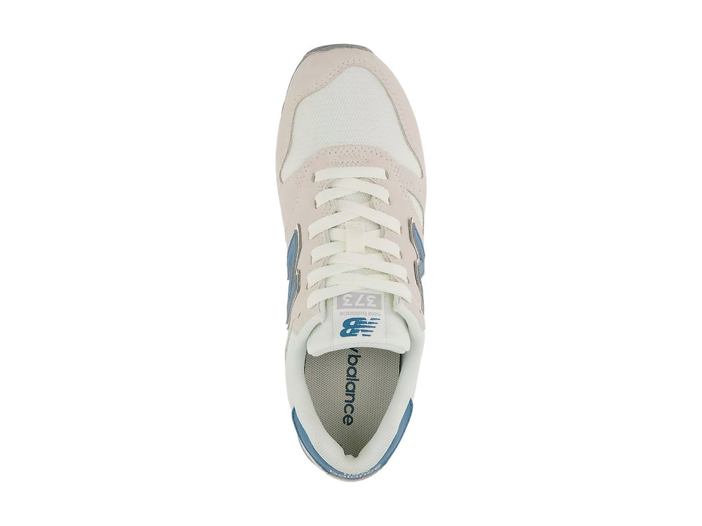 Tenis New Balance color beige Moonbeam con detalles en azul y suela blanca.