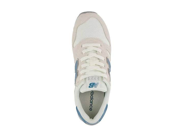 Tenis New Balance color beige Moonbeam con detalles en azul y suela blanca.