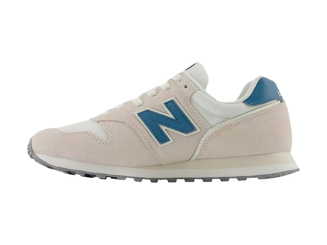 Tenis New Balance color beige Moonbeam con detalles en azul y suela blanca.