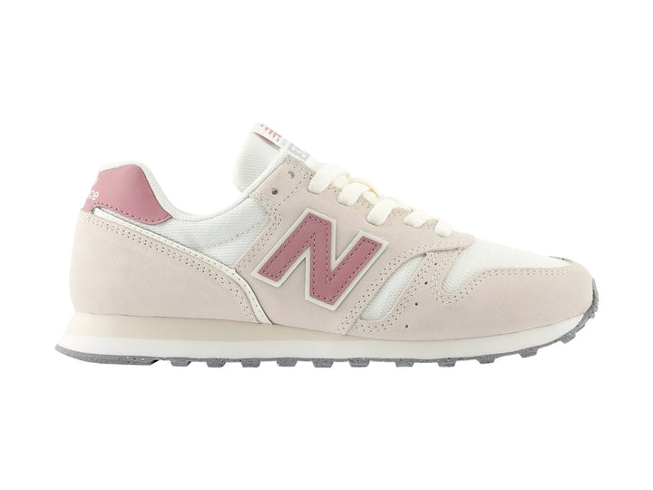 Tenis New Balance 373 color beige con detalles en rosa y suela blanca y gris.