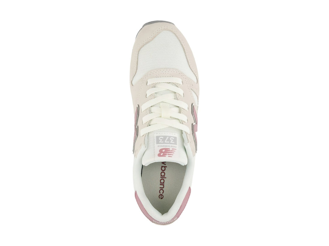Tenis New Balance 373 color beige con detalles en rosa y suela blanca y gris.