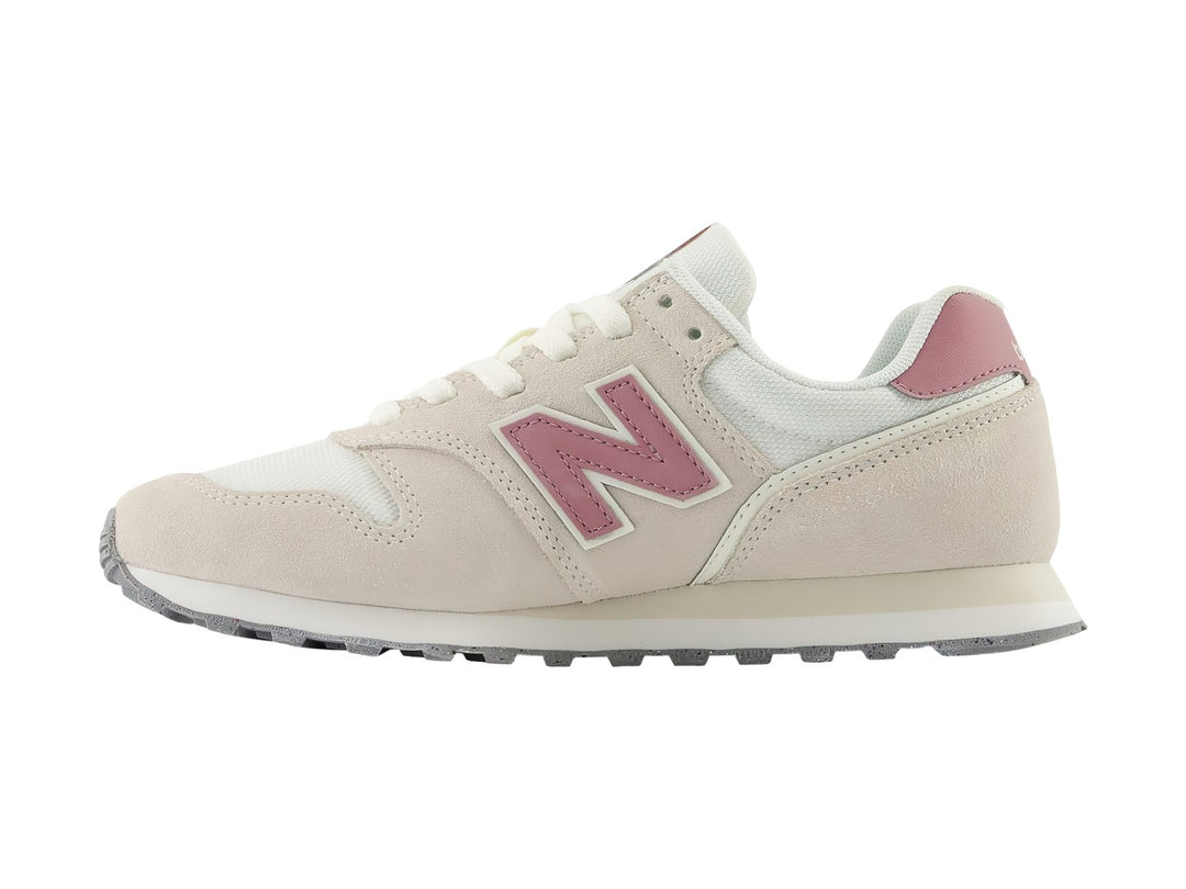 Tenis New Balance 373 color beige con detalles en rosa y suela blanca y gris.