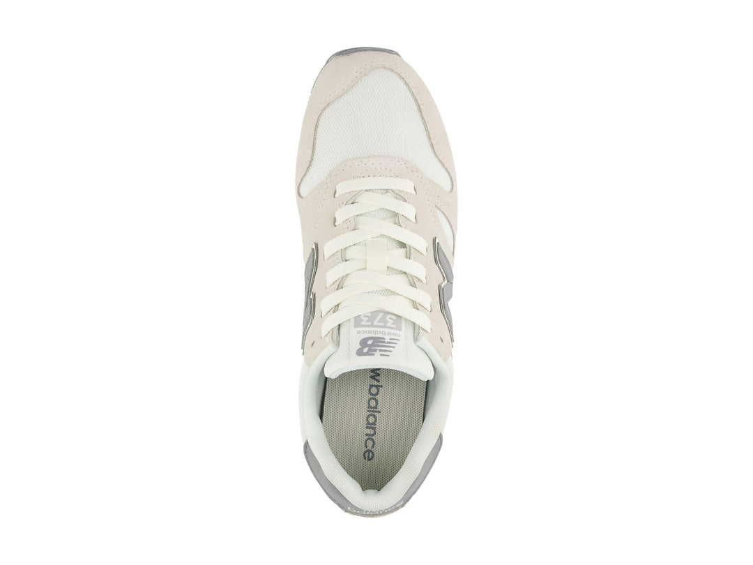 Tenis New Balance 373 color beige Moonbeam con detalles en gris y suela blanca.