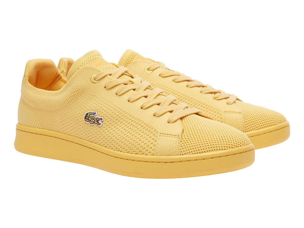Tenis amarillos Lacoste con textura de piqué y suela plana.