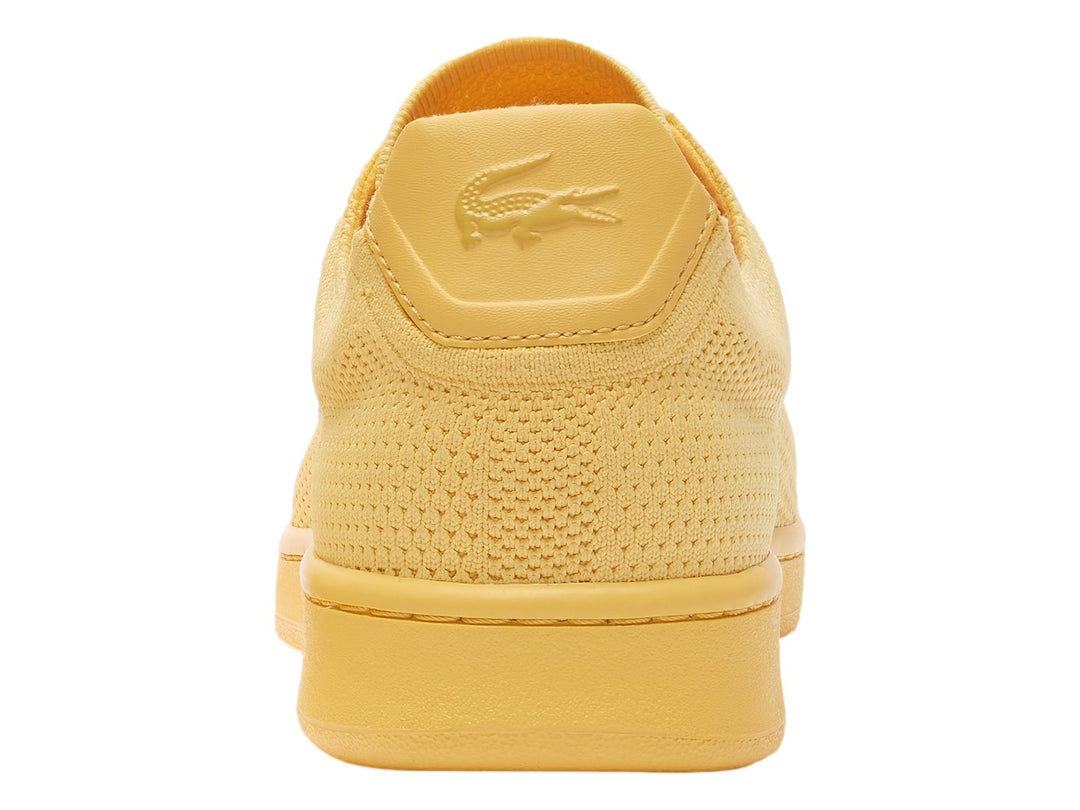 Tenis amarillos Lacoste con textura de piqué y suela plana.