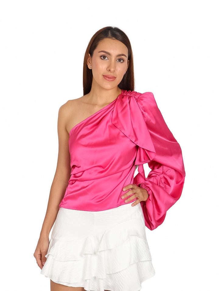 Blusa asimétrica color fushia brillante con manga larga abullonada en un solo hombro.