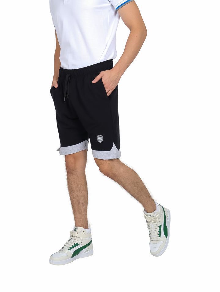 Hombre vistiendo shorts deportivos K-Swiss color negro con detalle gris en el borde inferior.