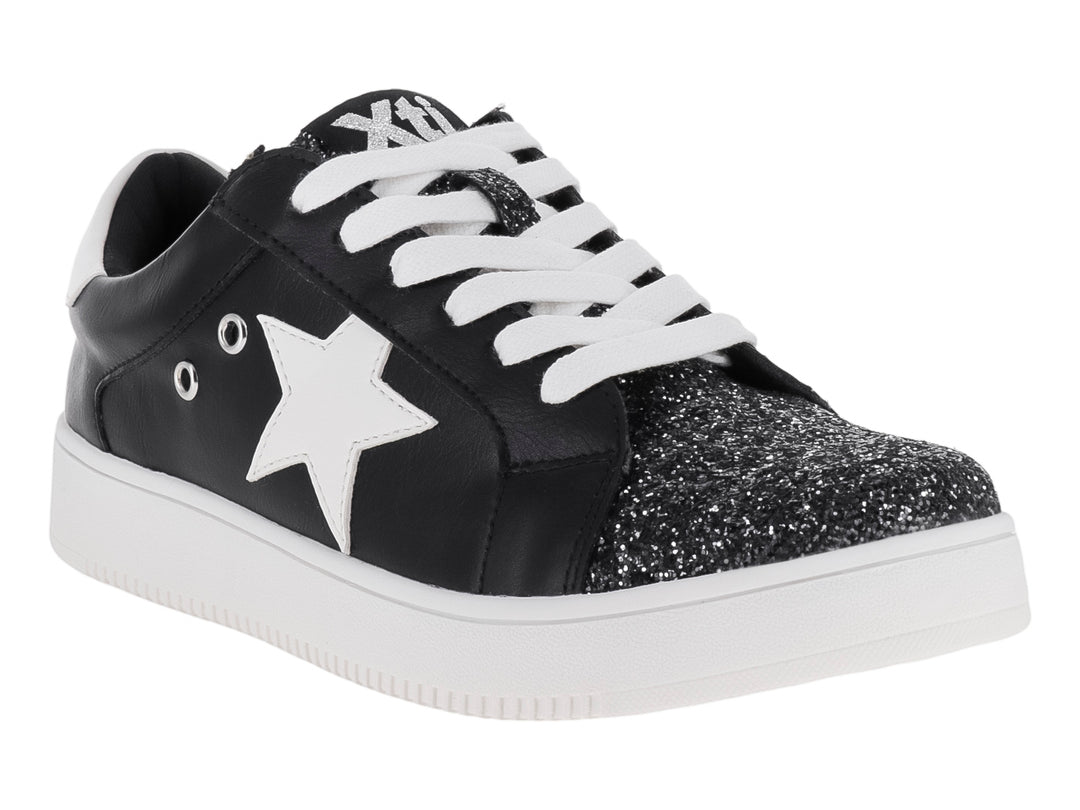 Tenis negros infantiles con estrella blanca, punta brillante y suela blanca.