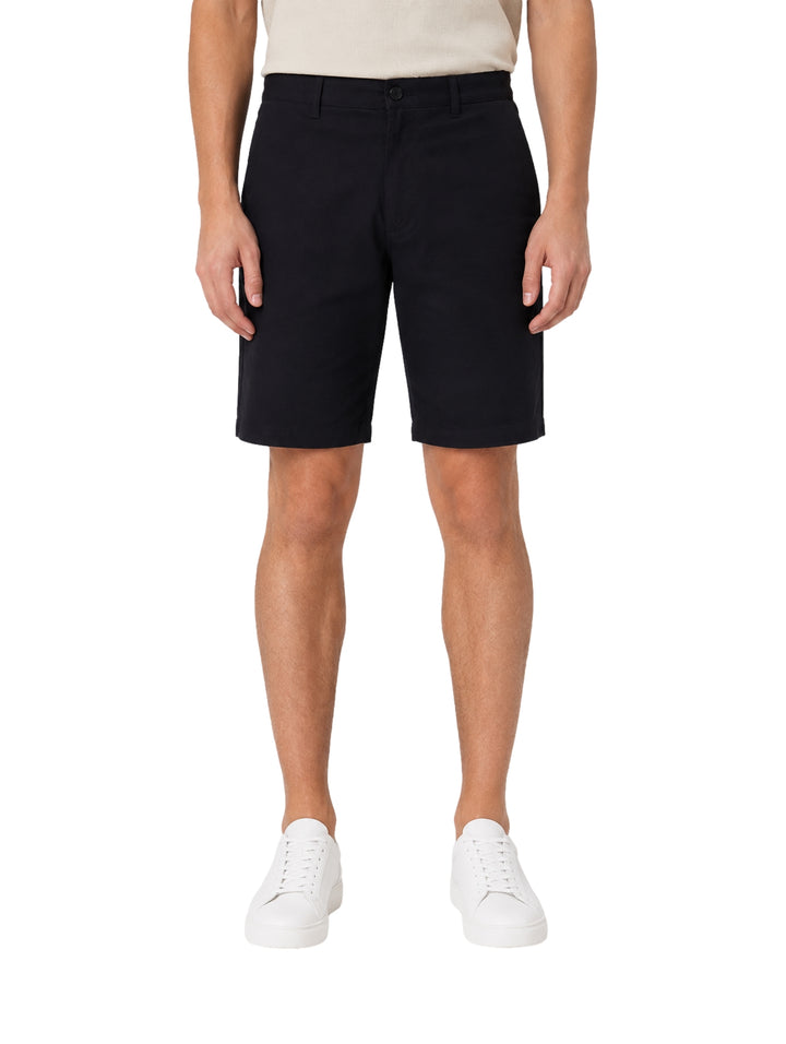 Hombre vistiendo shorts color navy de la marca Vertical Eagle y tenis blancos.