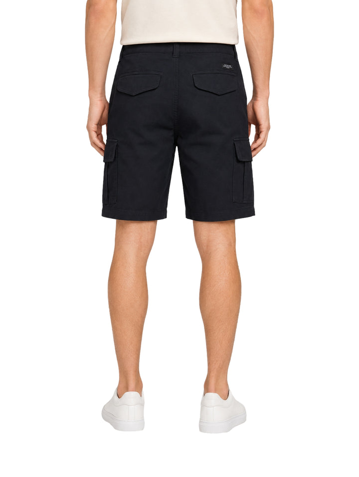 Hombre vistiendo shorts de surf color navy con bolsillos laterales y tenis blancos.