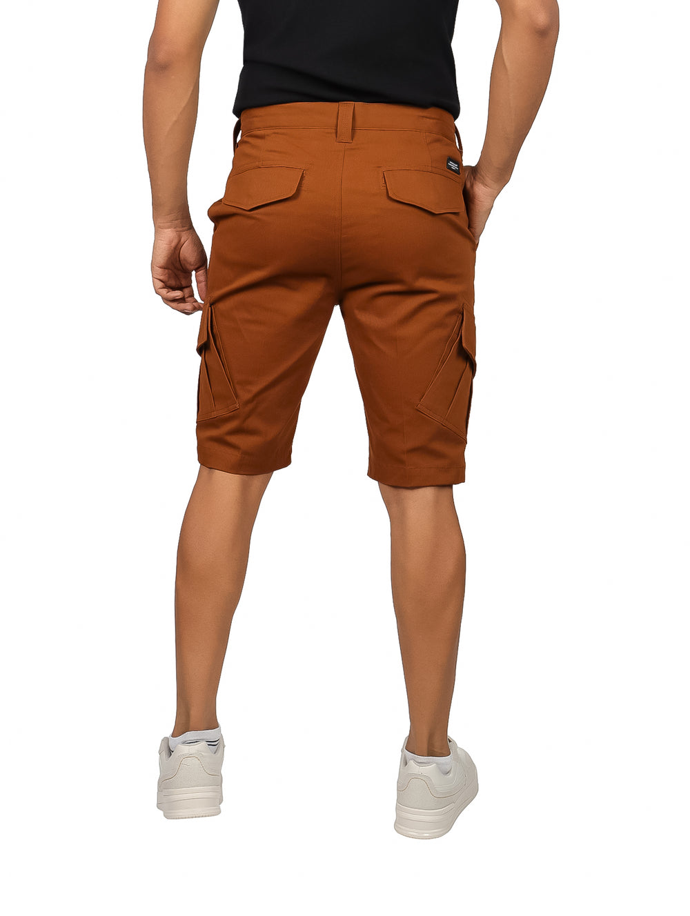 Hombre vistiendo shorts color tabaco con bolsillos laterales tipo cargo y tenis blancos.