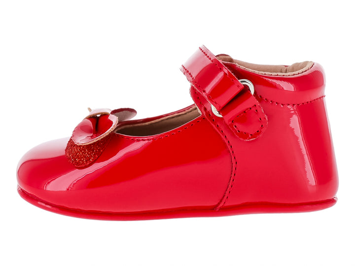 Zapato infantil color rojo brillante con acabado de charol, correa ajustable y moño decorativo.