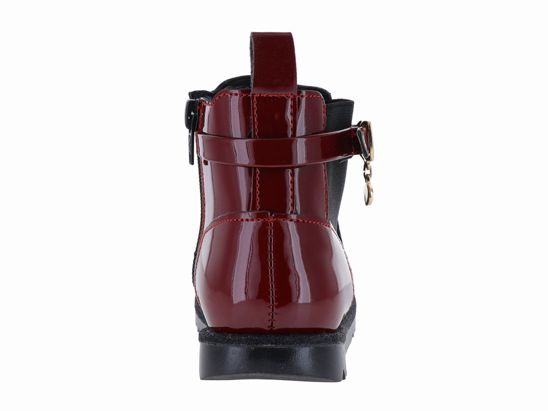 Botín rojo de charol con suela negra dentada y detalle de hebilla dorada.