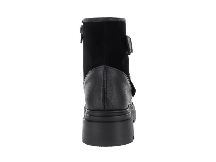 Bota negra de piel con suela de plataforma track y dos hebillas decorativas plateadas.