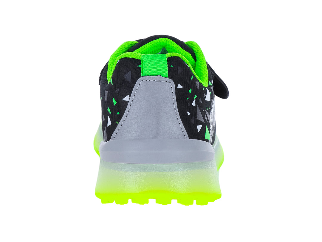 Tenis infantiles negros con suela verde neón y diseño de esqueleto de dinosaurio.