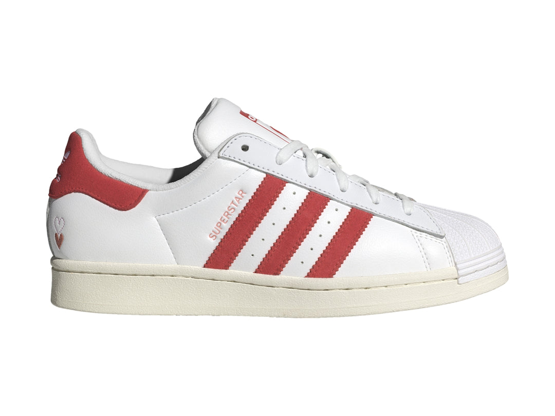 Tenis Adidas Superstar blancos con tres franjas rojas laterales y detalle rojo en el talón.