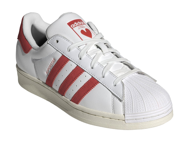 Tenis Adidas Superstar blancos con tres franjas rojas laterales y detalle rojo en el talón.