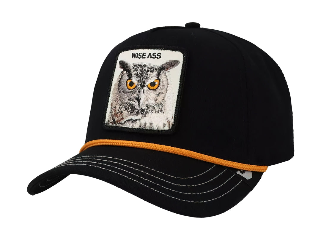 Gorra negra Goorin Bros con parche frontal de un búho y detalle de cordón naranja sobre la visera.