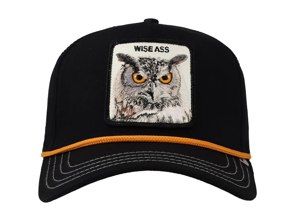 Gorra negra Goorin Bros con parche frontal de un búho y detalle de cordón naranja sobre la visera.