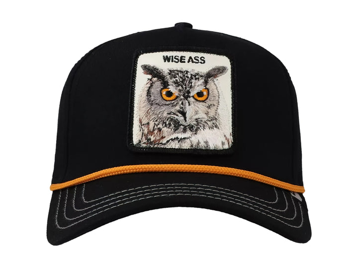 Gorra negra Goorin Bros con parche frontal de un búho y detalle de cordón naranja sobre la visera.