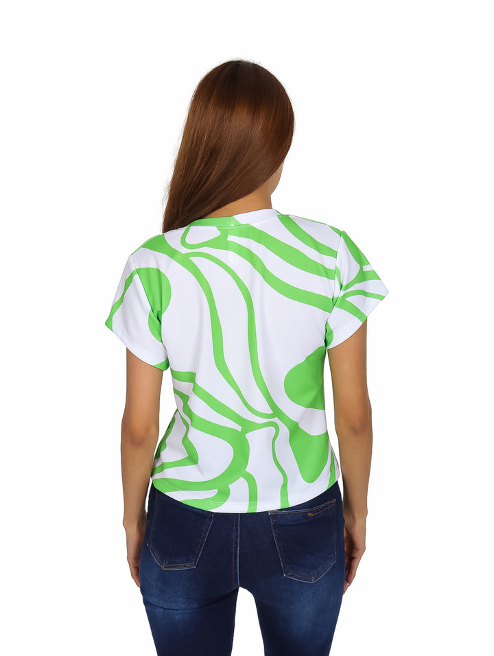 Mujer vistiendo blusa blanca con estampado abstracto verde y jeans azules.