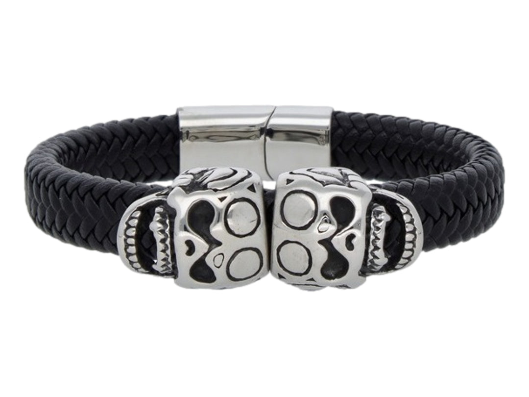 Pulsera de cuero negro trenzado con cierre metálico y dos detalles de calaveras plateadas en el centro.
