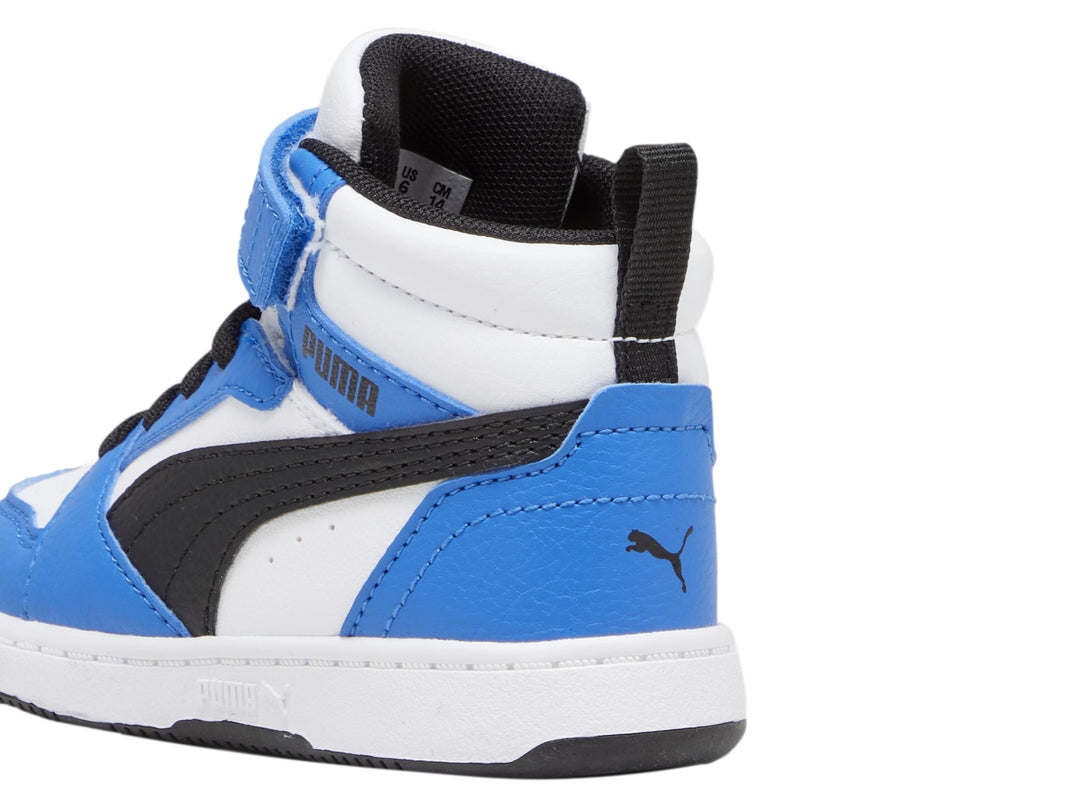 Tenis PUMA Rebound V6 Mid para niño en colores blanco, azul y negro con correa de velcro.