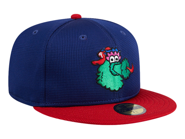 Gorra New Era azul con visera roja y un personaje verde bordado en el frente.
