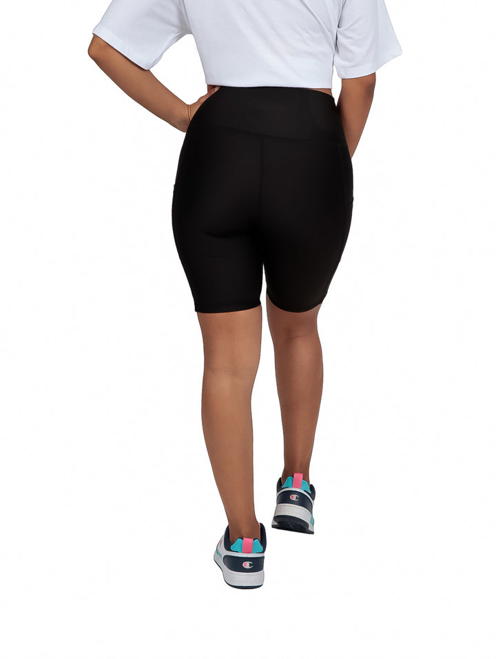Mujer vistiendo shorts biker color negro de cintura alta y tenis blancos.