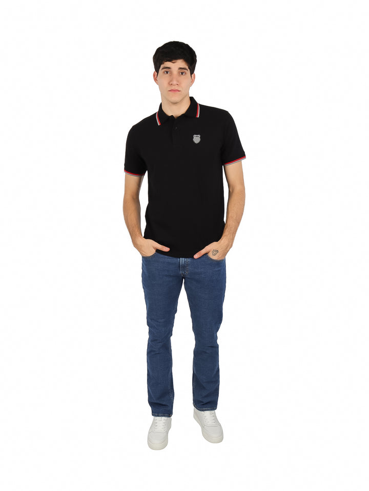 Hombre vistiendo playera polo K-SWISS color negro con detalles rojos y blancos en el cuello y mangas.