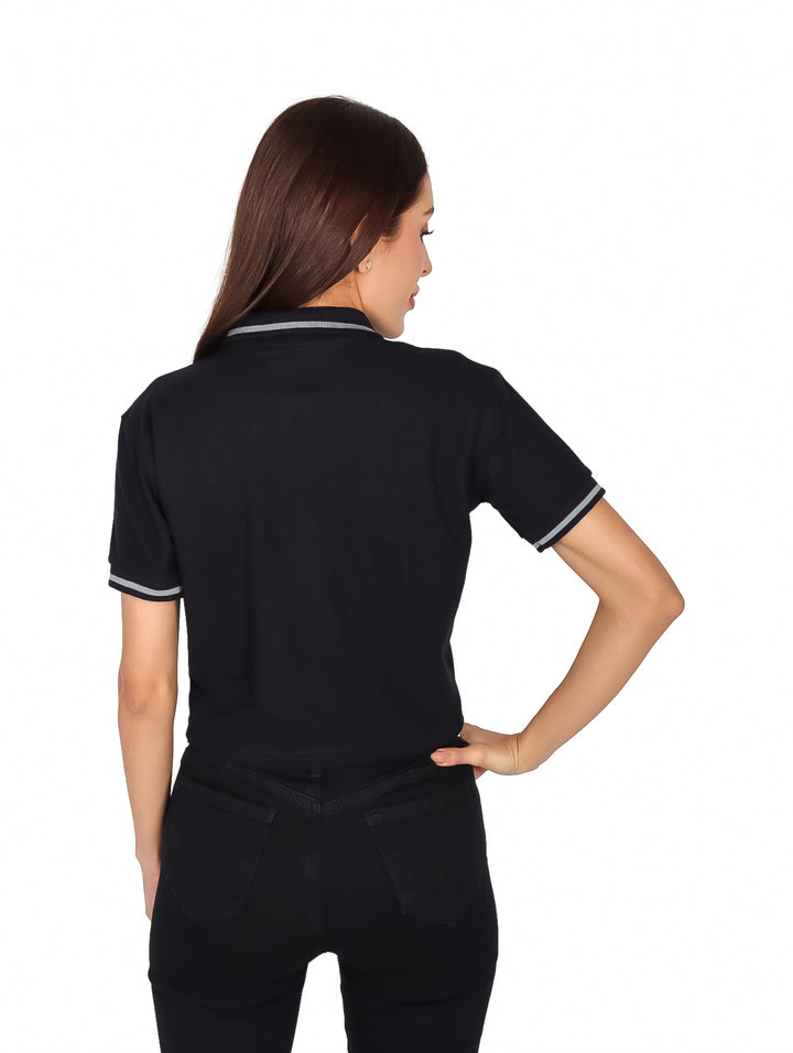 Mujer vistiendo playera polo corta color negro con detalles blancos en cuello y mangas de la marca K-Swiss.