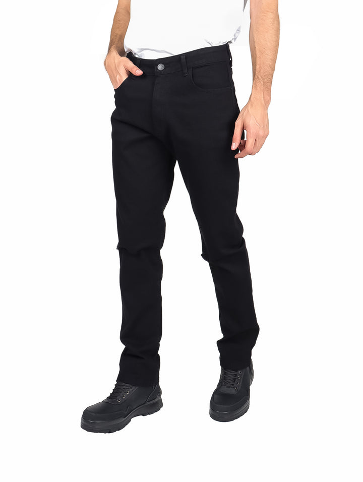 Hombre vistiendo pantalones jeans slim fit de color negro y calzado negro sobre fondo blanco.