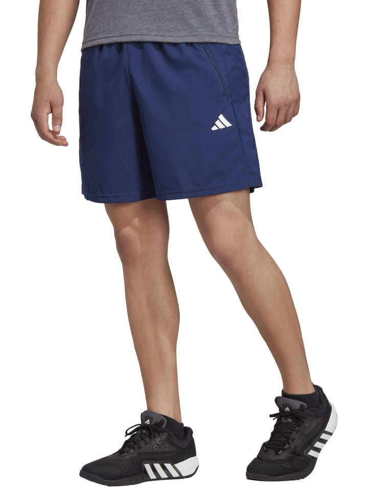 Hombre vistiendo shorts deportivos Adidas en color azul oscuro.