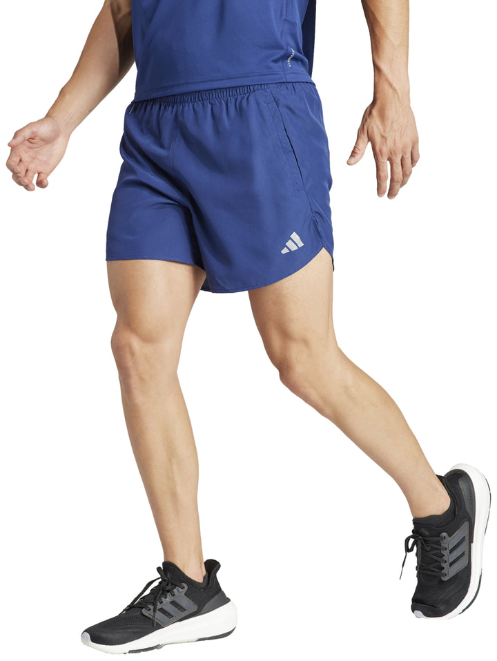 Hombre vistiendo shorts deportivos Adidas en color azul oscuro para correr.