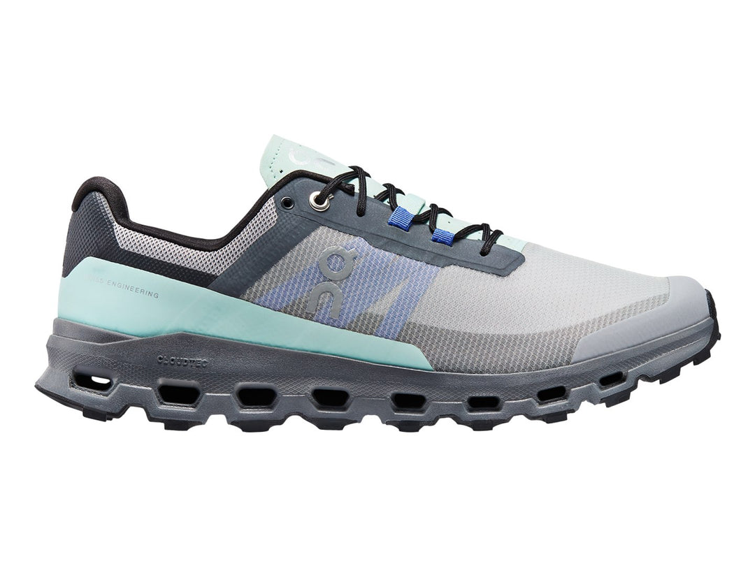 Tenis deportivos On Cloud color gris con detalles en azul claro y suela gruesa texturizada.