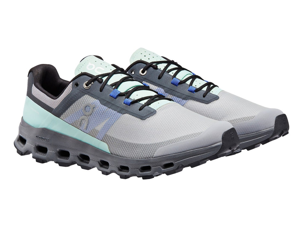 Tenis deportivos On Cloud color gris con detalles en azul claro y suela gruesa texturizada.