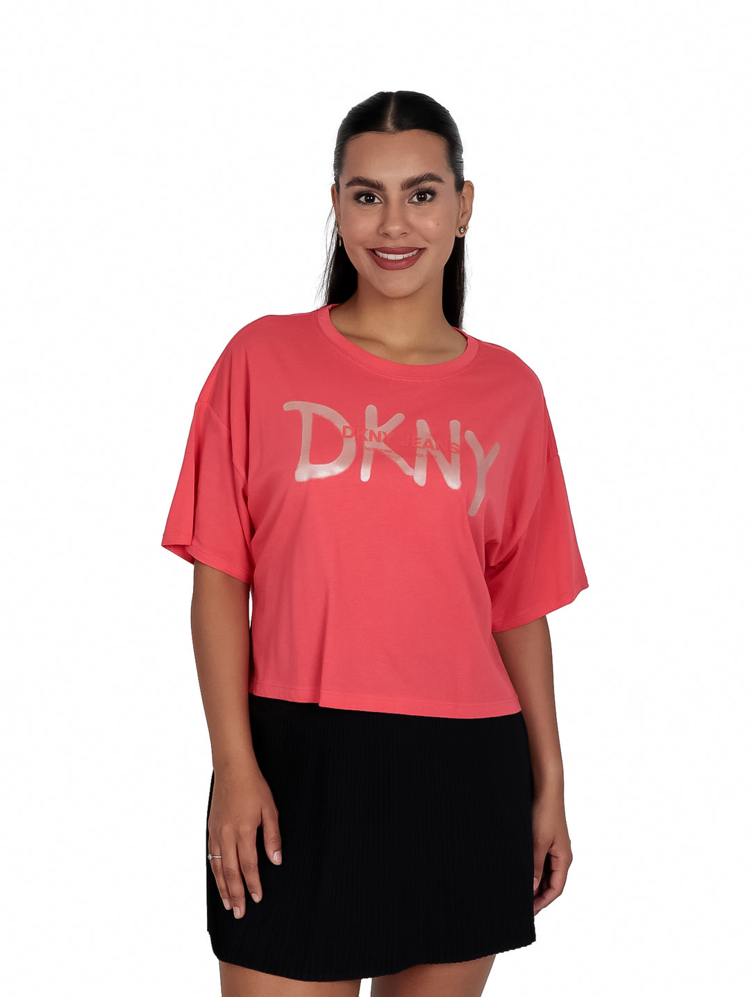 Mujer vistiendo camiseta corta color coral con logo DKNY en dorado y falda negra.