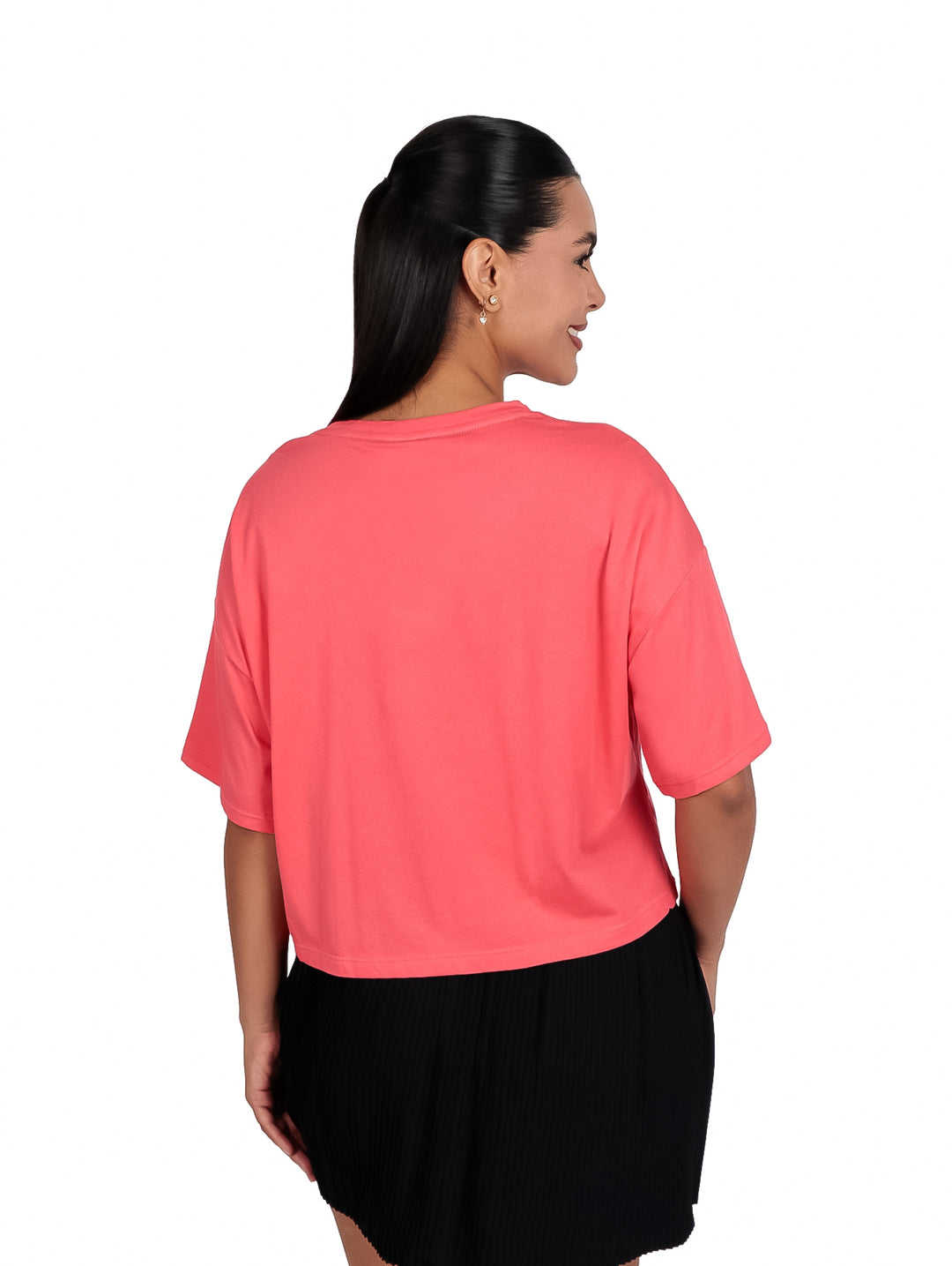 Mujer vistiendo camiseta corta color coral con logo DKNY en dorado y falda negra.