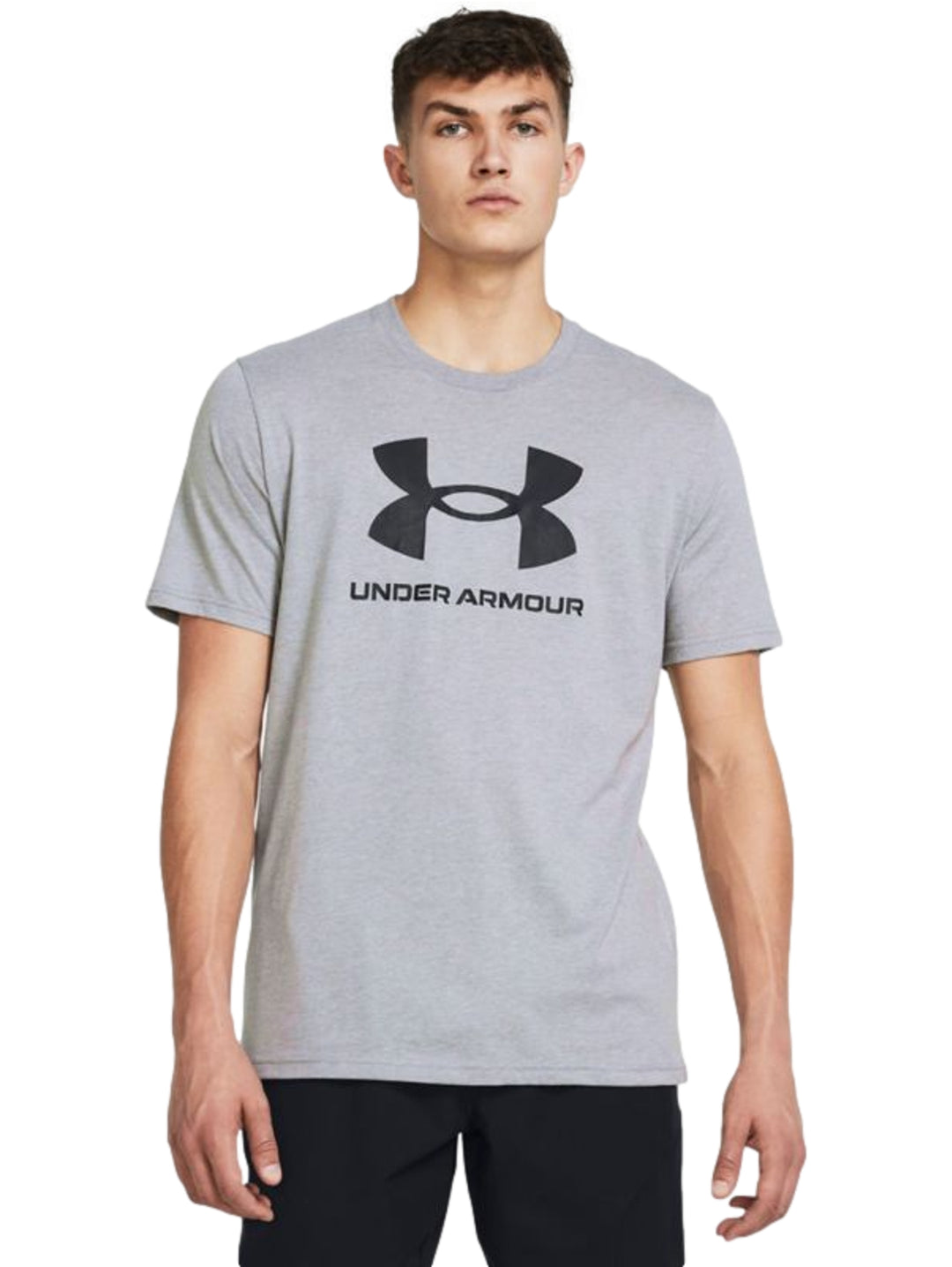 Hombre vistiendo una playera deportiva de color gris con el logotipo de Under Armour en negro en el pecho.