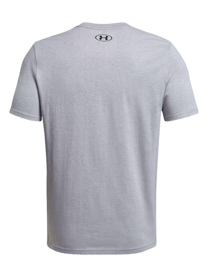 Hombre vistiendo una playera deportiva de color gris con el logotipo de Under Armour en negro en el pecho.