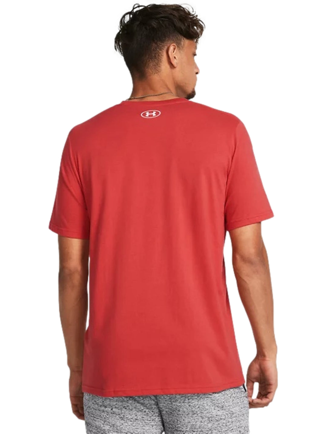 Hombre vistiendo una playera deportiva Under Armour de color rojo con logotipo blanco en el pecho.