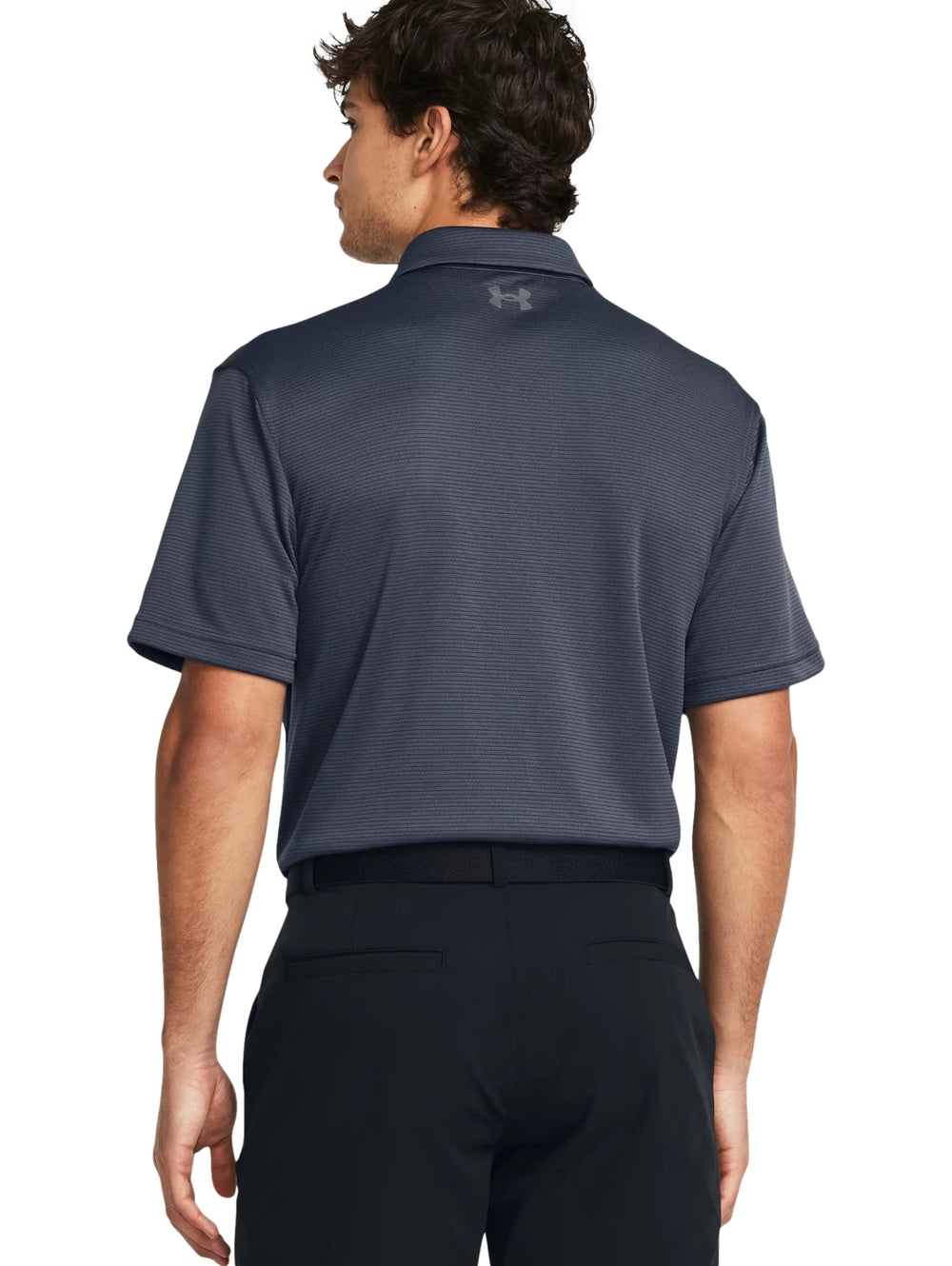 Hombre vistiendo polo deportivo Under Armour de color gris oscuro con cuello y manga corta.