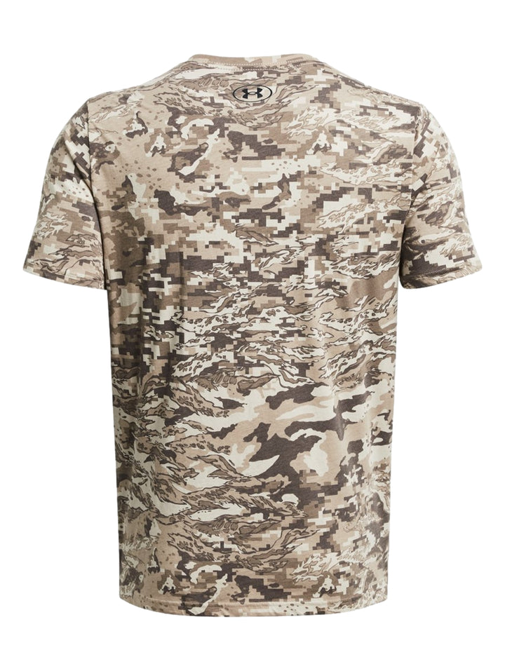 Hombre vistiendo camiseta Under Armour de manga corta con estampado de camuflaje en tonos marrón y beige.