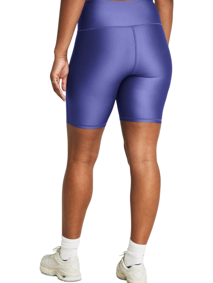 Mujer vistiendo mallas deportivas cortas Under Armour en color morado brillante con cintura alta.
