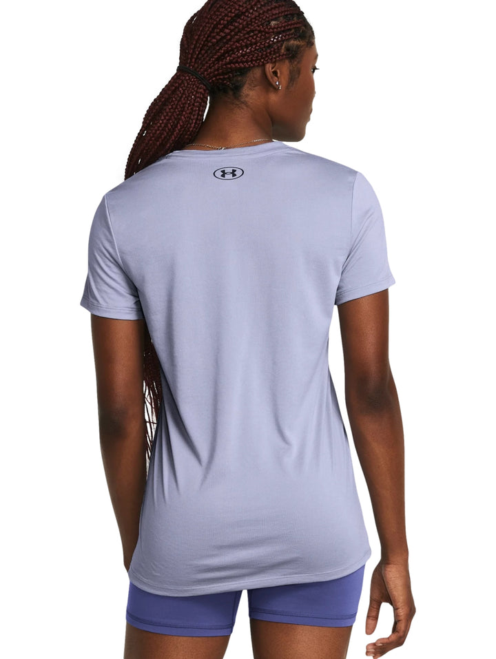 Mujer vistiendo una camiseta deportiva de manga corta color morado claro con logotipo de Under Armour en el pecho.