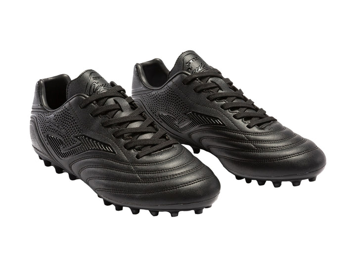 Botín de fútbol Joma Agus 2321 color negro con tacos para pasto natural.