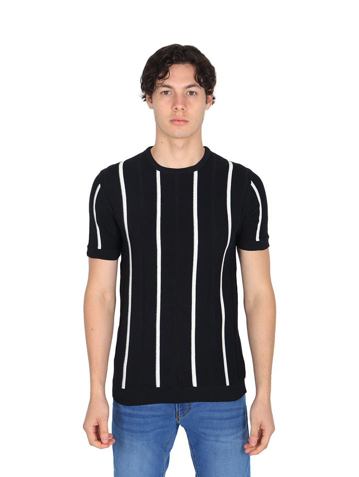 Hombre vistiendo playera negra con rayas verticales blancas y pantalones azules.