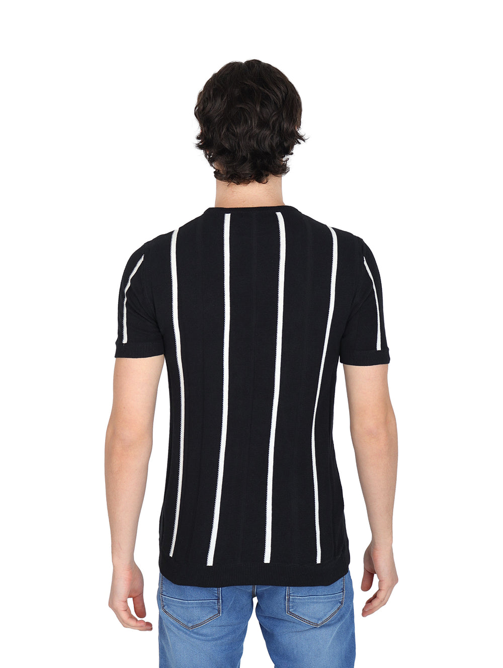 Hombre vistiendo playera negra con rayas verticales blancas y pantalones azules.