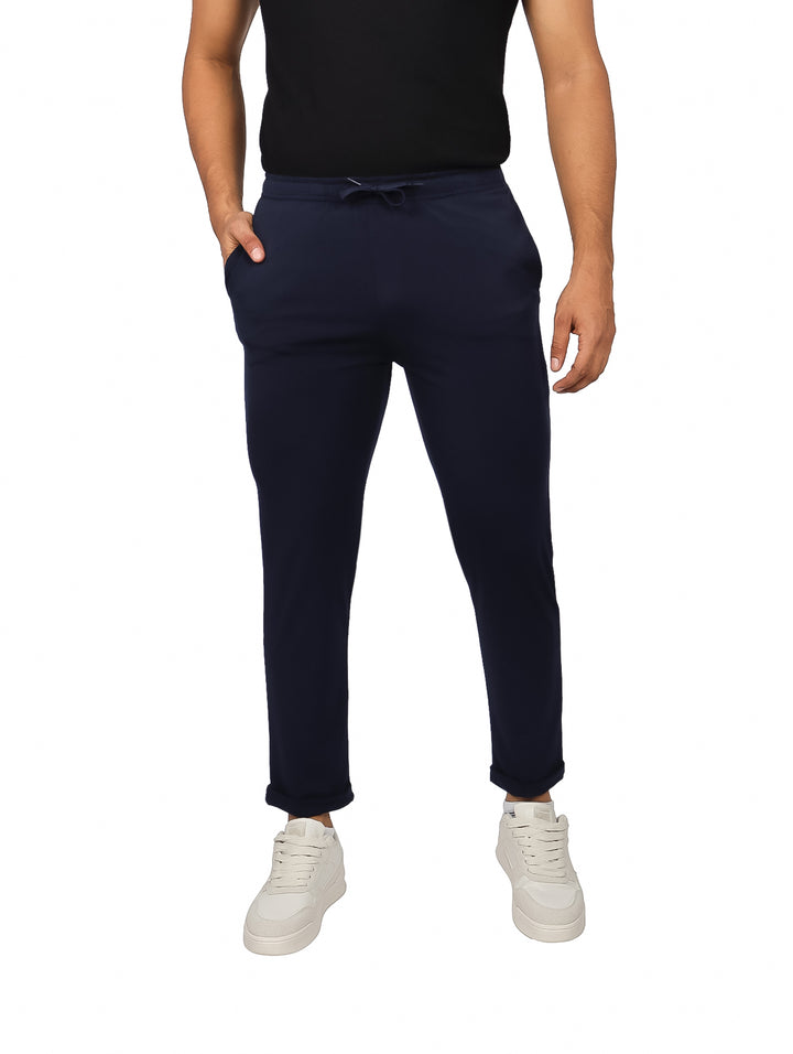 Hombre vistiendo pantalones jogger color azul marino de corte ajustado y calzado blanco.