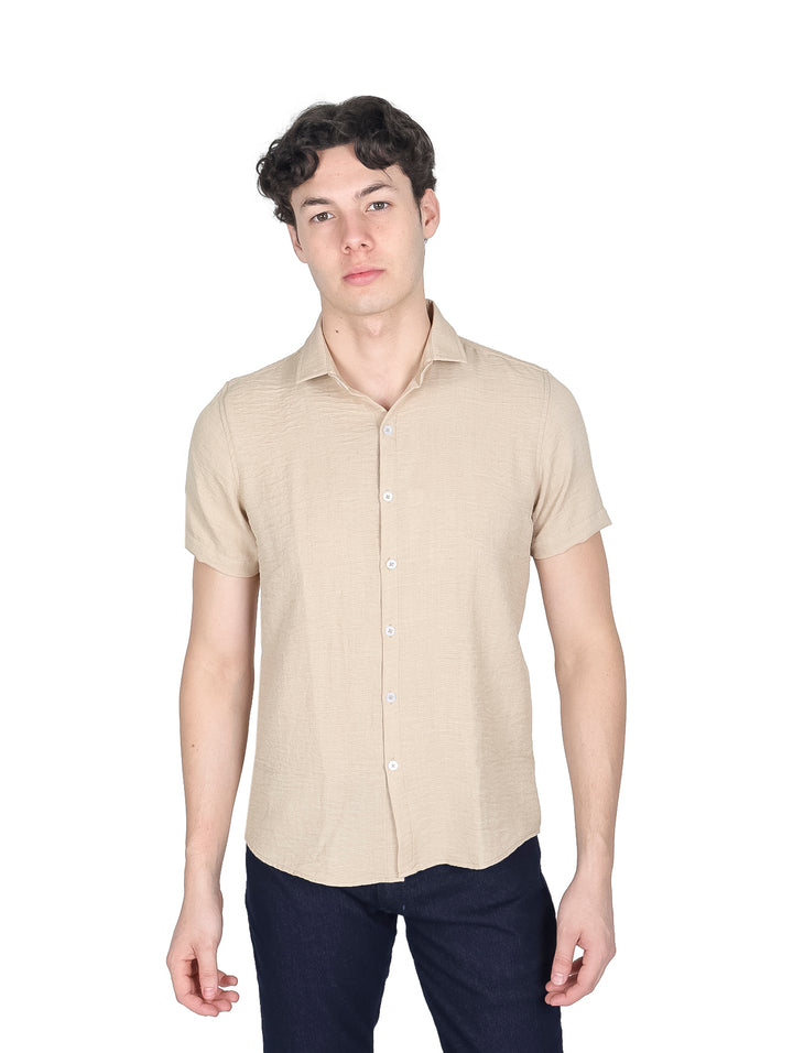Hombre vistiendo camisa de manga corta color beige con botones y pantalones azul marino.